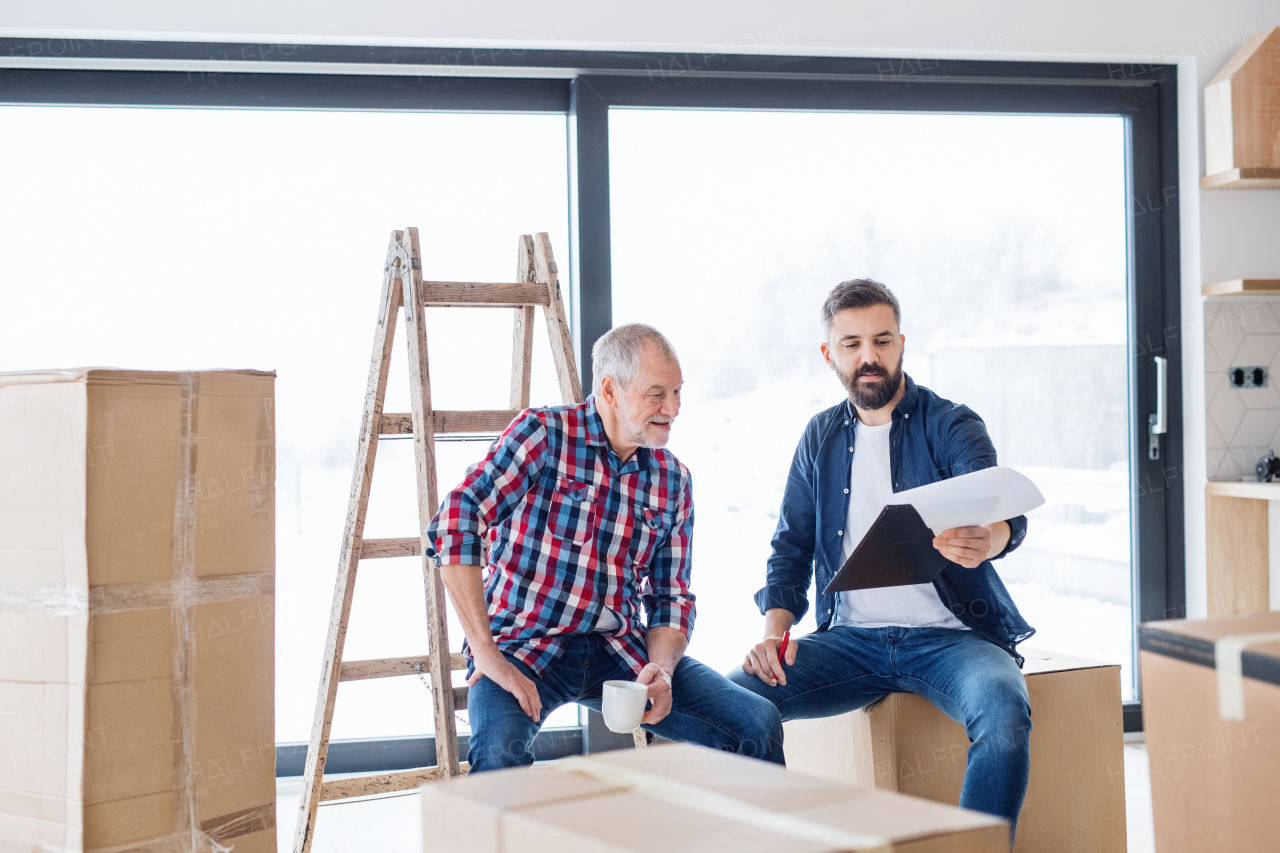 A cheerful senior man helping his mature son with furnishing new house, a new home concept.