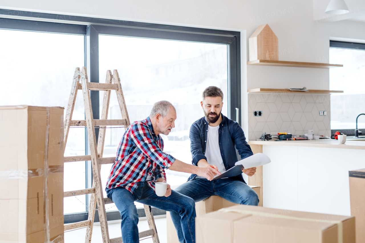 A cheerful senior man helping his mature son with furnishing new house, a new home concept.