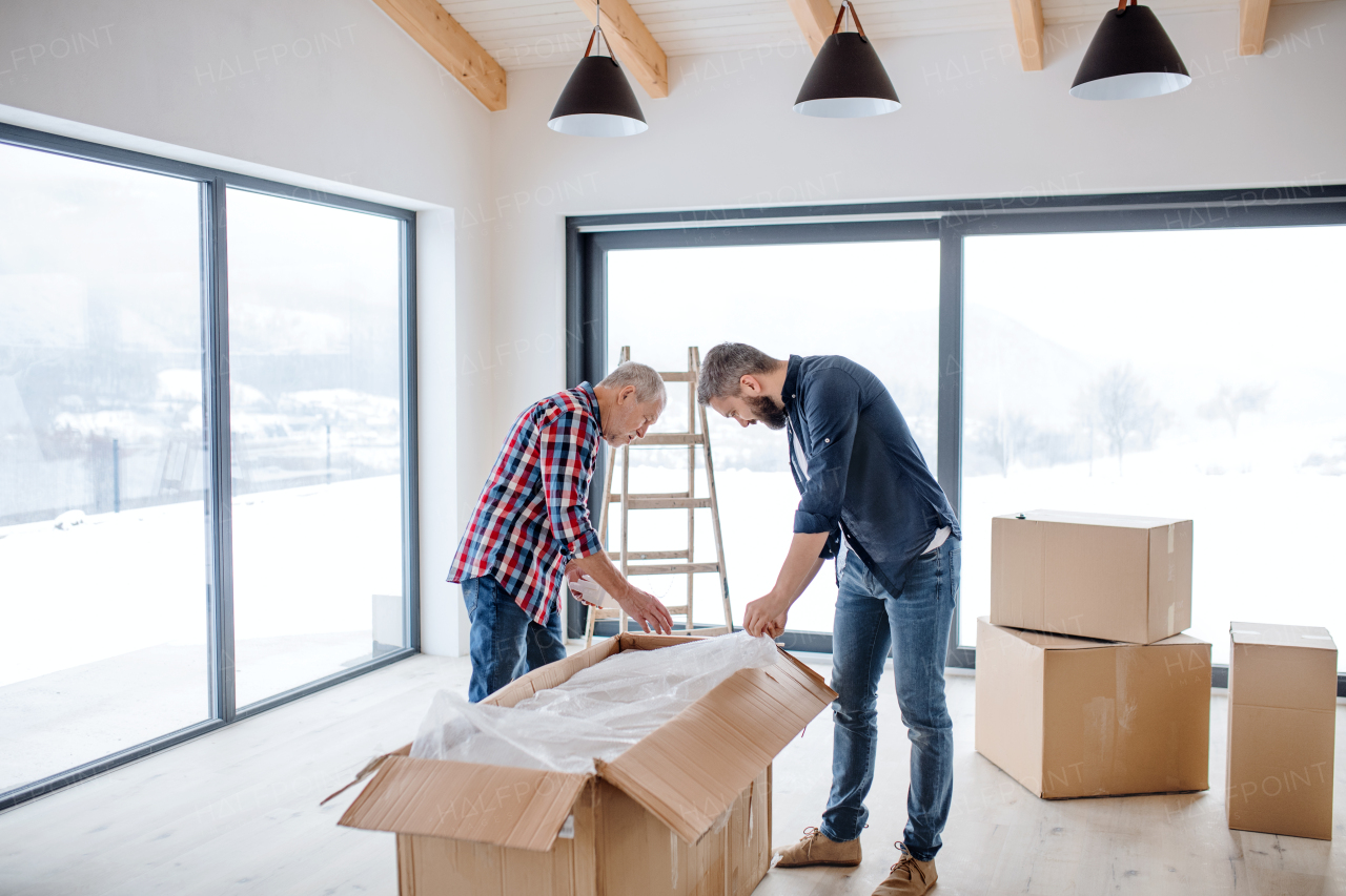 A cheerful senior man helping his mature son with furnishing new house, a new home concept.