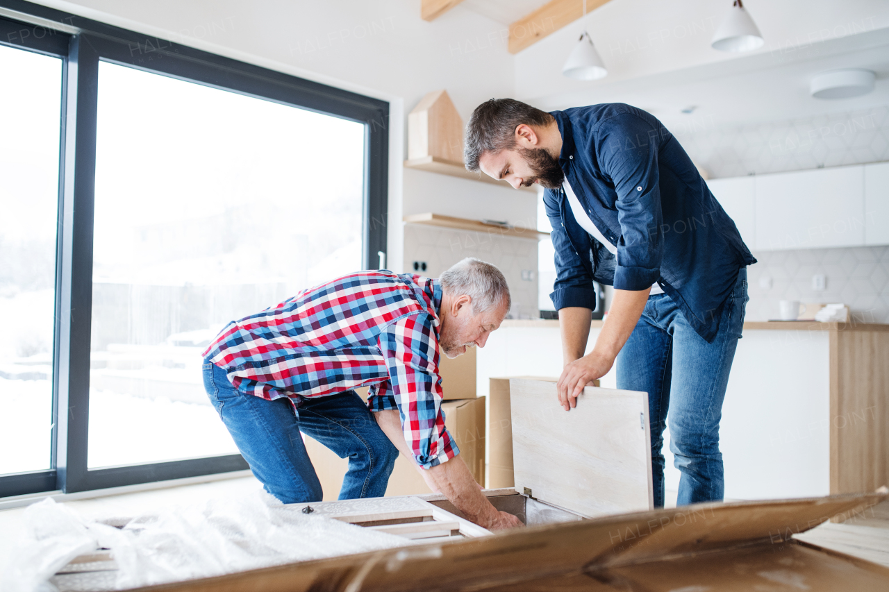 A hipster mature man with his senior father assembling furniture, a new home concept.