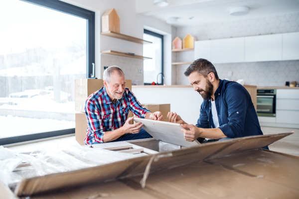 A hipster mature man with his senior father assembling furniture, a new home concept.