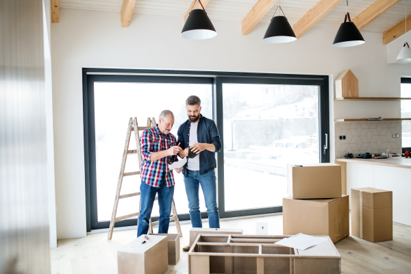 A hipster mature man with his senior father assembling furniture, a new home concept.