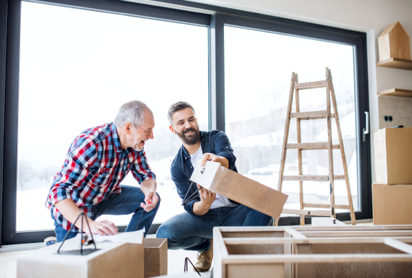 A hipster mature man with his senior father assembling furniture, a new home concept.