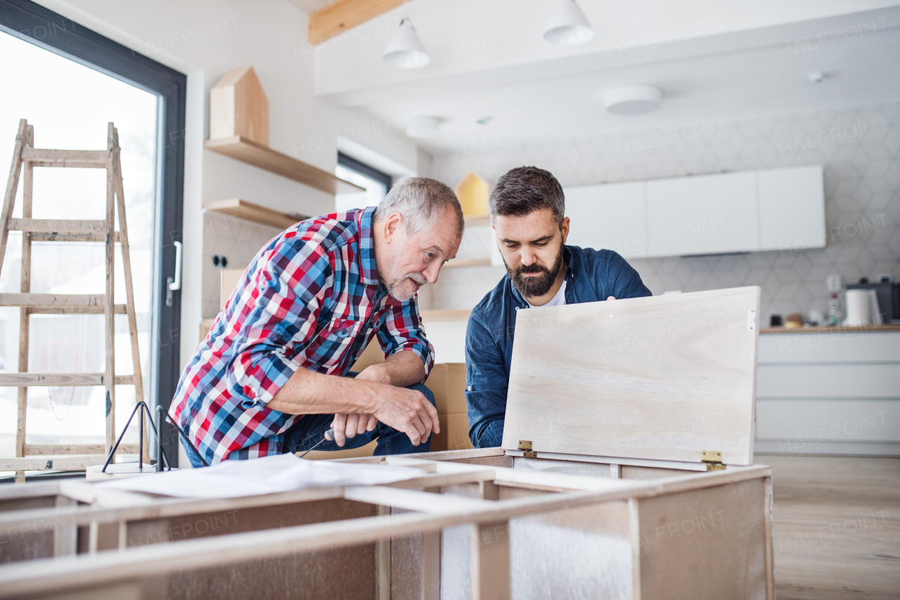 A hipster mature man with his senior father assembling furniture, a new home concept.