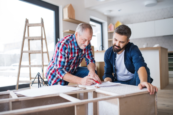 A hipster mature man with his senior father assembling furniture, a new home concept.