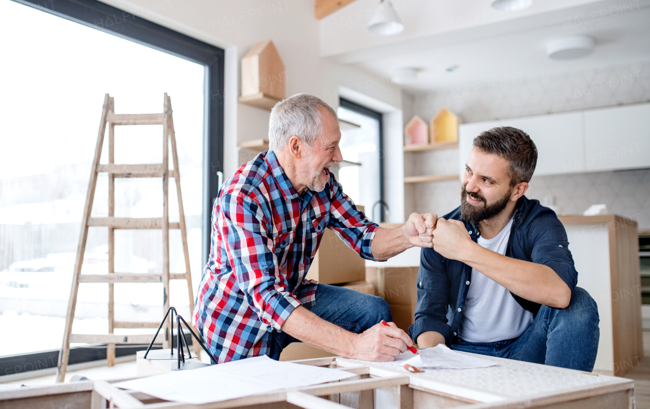 A hipster mature man with his senior father assembling furniture, a new home concept.