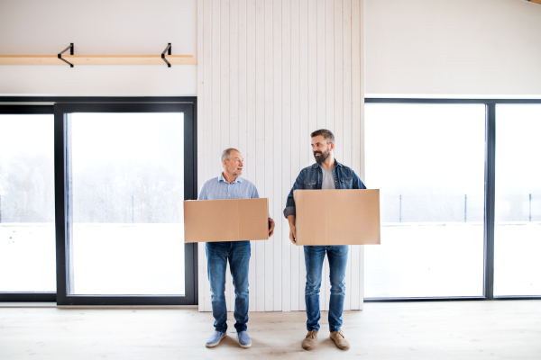 A senior man helping his mature son with furnishing new house, a new home concept.