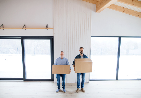 Two men holding cardboard boxes in front of them when furnishing new house, a new home concept.