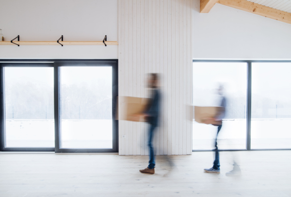 Unrecognizable men walking with cardboard boxes when furnishing new house. Intentional motion blur.