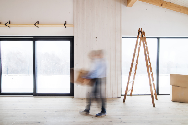 An unrecognizable man walking with cardboard boxes when furnishing new house. Intentional motion blur.