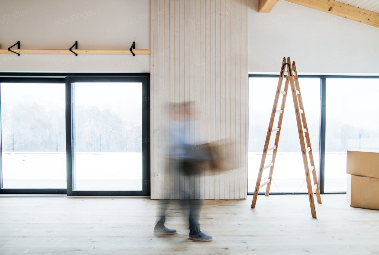 An unrecognizable man walking with cardboard boxes when furnishing new house. Intentional motion blur.