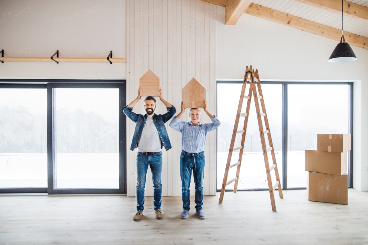 Two men holding small wooden houses on their heads when furnishing new house, a new home concept.