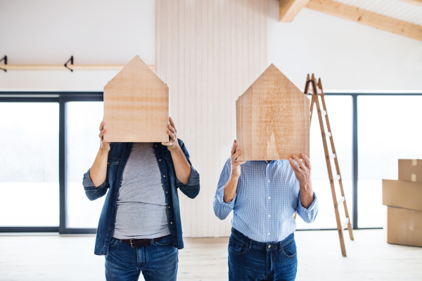 A senior man helping his mature son with furnishing new house, having fun. A new home concept.