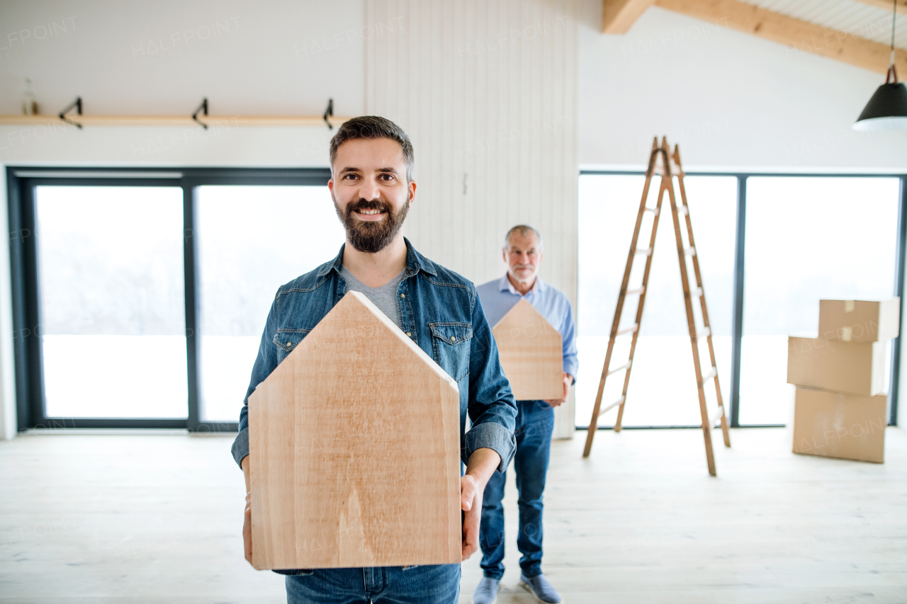 A senior man helping his mature son with furnishing new house, having fun. A new home concept.