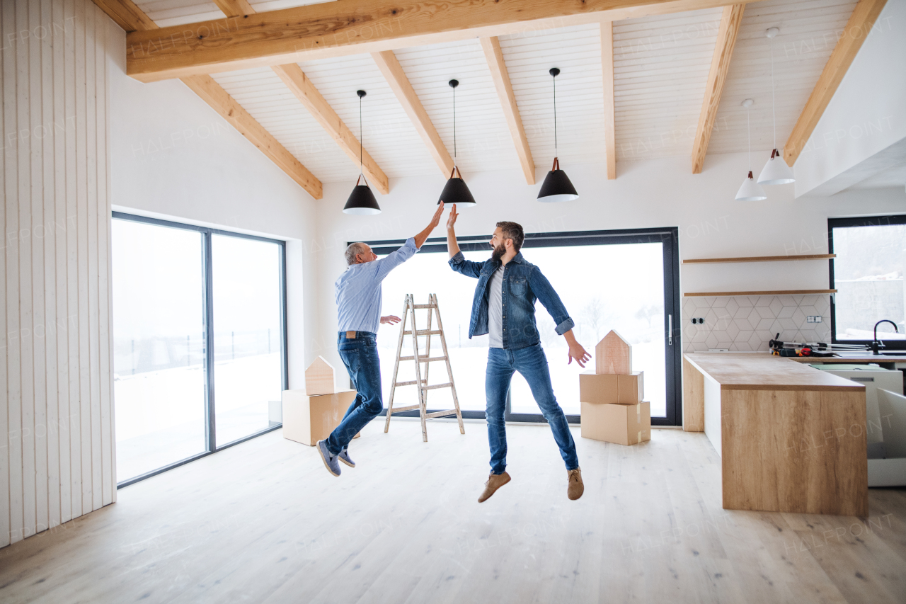 A cheerful mature man jumping with his senior father in new house, a new home concept.