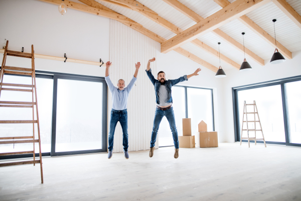 A cheerful mature man jumping with his senior father in new house, a new home concept.