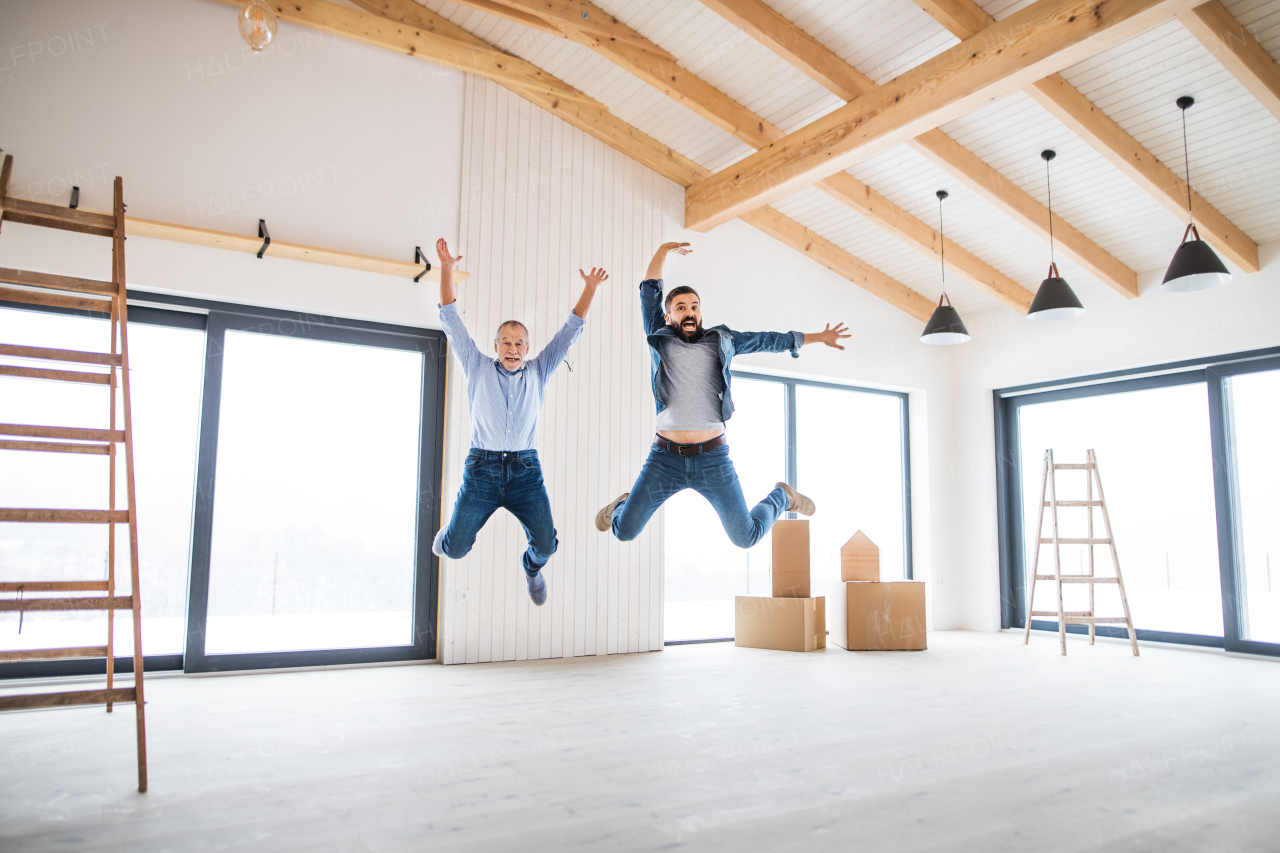 A cheerful mature man jumping with his senior father in new house, a new home concept.