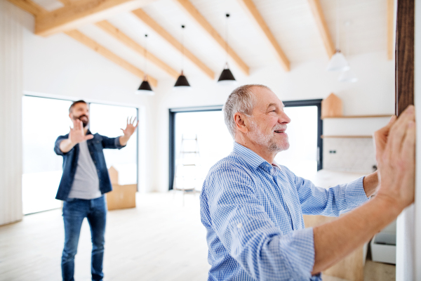 A senior man helping his son hanging up pictures on a wall, a new home concept.