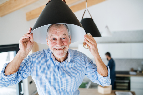 A cheerful senior man helping his mature son with furnishing new house, a new home concept.