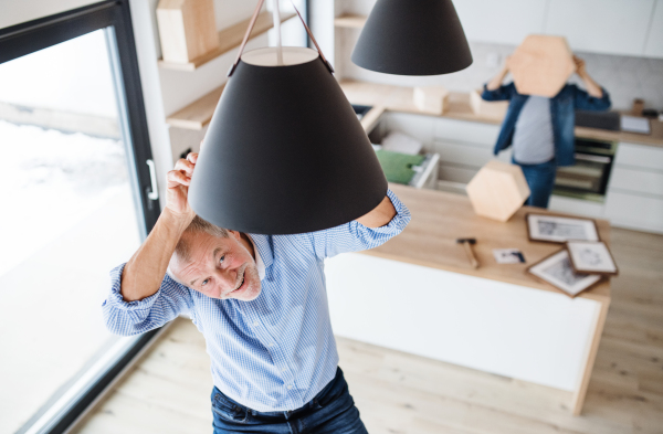 A cheerful senior man helping his mature son with furnishing new house, a new home concept.