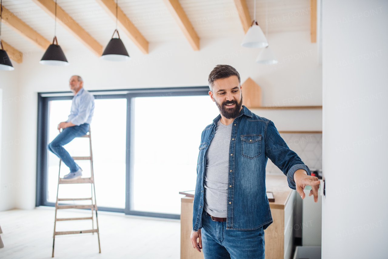 A cheerful senior man helping his mature son with furnishing new house, a new home concept.