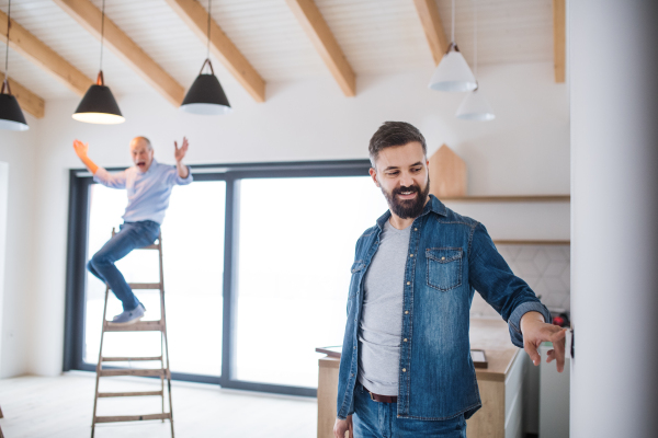 A cheerful senior man helping his mature son with furnishing new house, a new home concept.