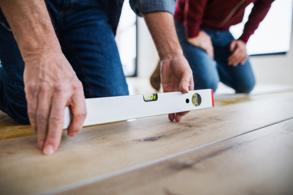 A midsection of mature man with his senior father laying vinyl flooring, a new home concept.