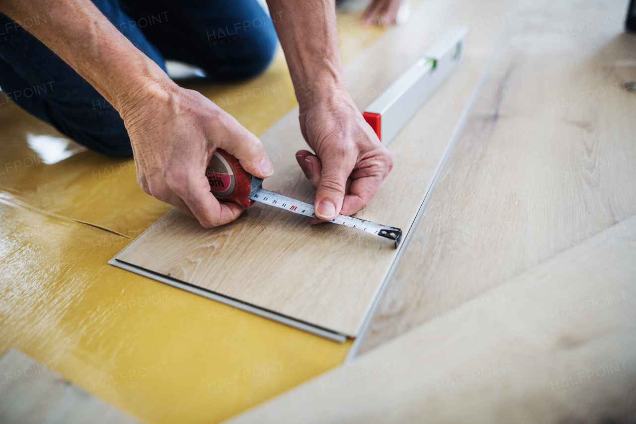 A midsection of unrecognizable senior man laying vinyl flooring, a new home concept.