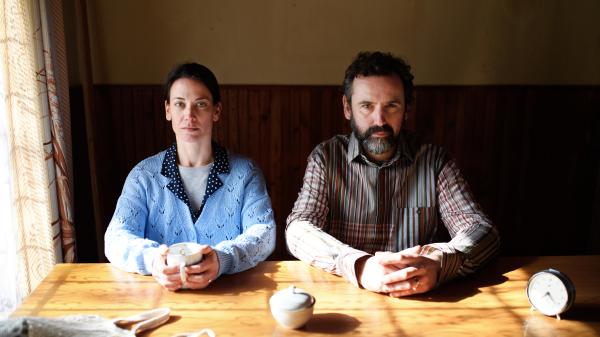 Portrait of poor mature couple looking at camera indoors at home, poverty concept.