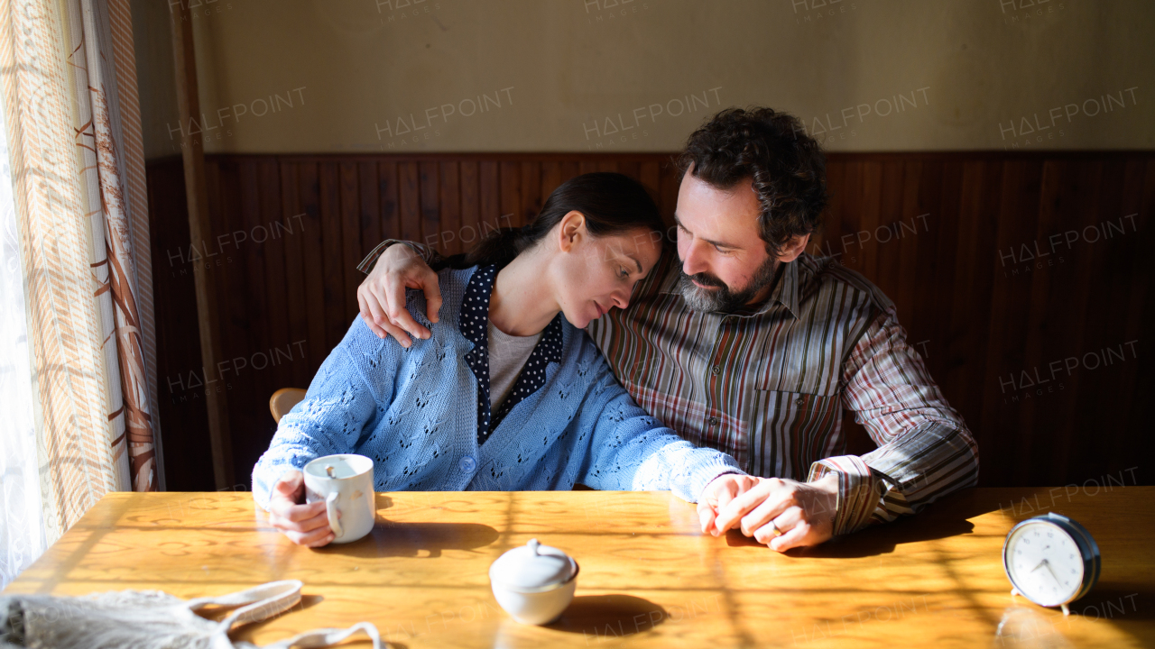 A portrait of happy poor mature couple resting indoors at home, poverty concept.