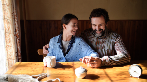 A portrait of happy poor mature couple resting indoors at home, poverty concept.