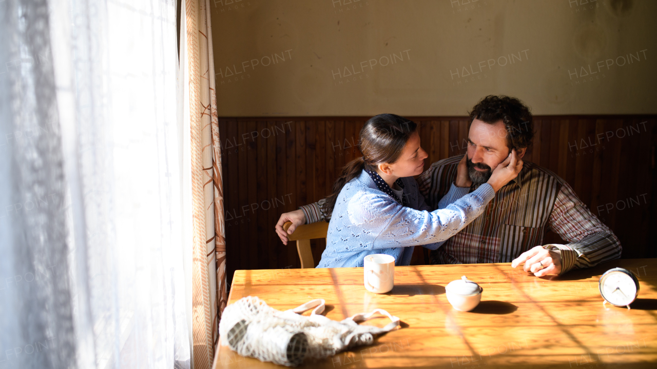 A portrait of happy poor mature couple resting indoors at home, poverty concept.