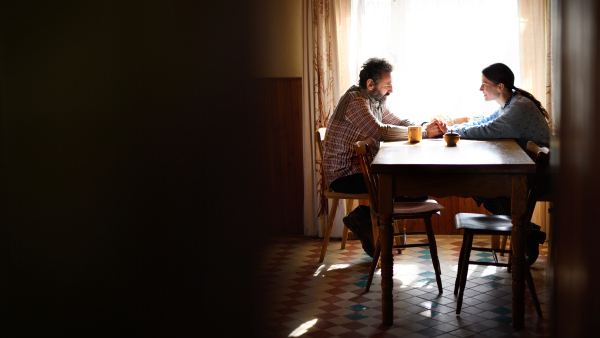 A portrait of poor mature couple talking indoors at home, poverty concept.