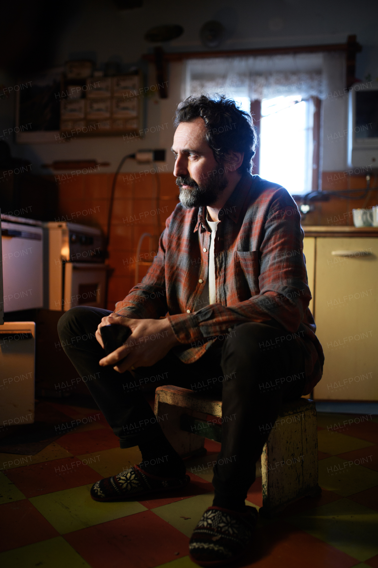 A portrait of poor mature man sitting indoors at home, poverty concept.