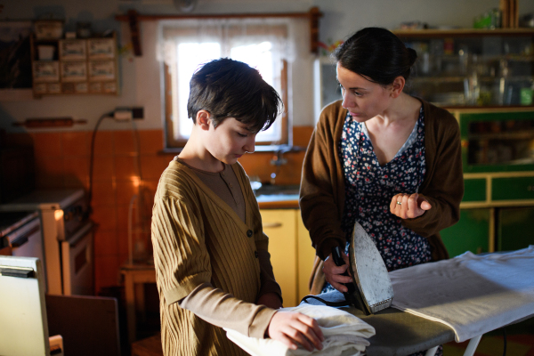 Poor mature mother scolding sad small daughter indoors at home, poverty concept.