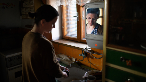 Portrait of poor mature woman washing dishes indoors at home, poverty concept.