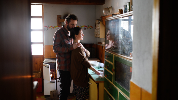 Portrait of sad poor mature couple hugging indoors at home, poverty concept.