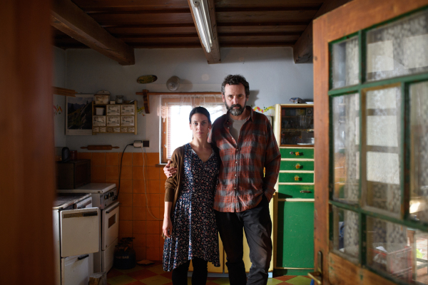 Portrait of sad poor mature couple looking at camera indoors at home, poverty concept.