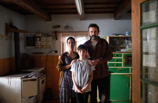 Portrait of poor mature couple with small daughter indoors in kitchen at home, poverty concept.