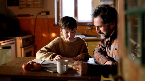 A poor mature father and small daughter learning indoors at home, poverty concept.