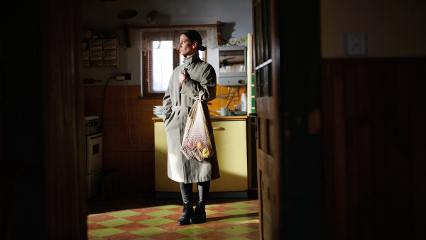 A portrait of poor mature woman with shopping indoors at home, poverty concept.