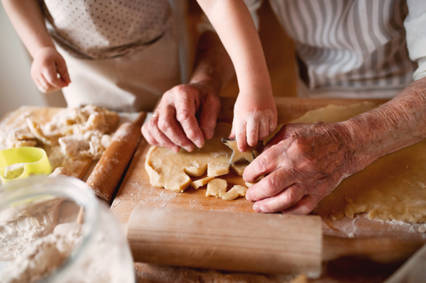 A midsection of senior great grandmother with small toddler boy making cakes at home.