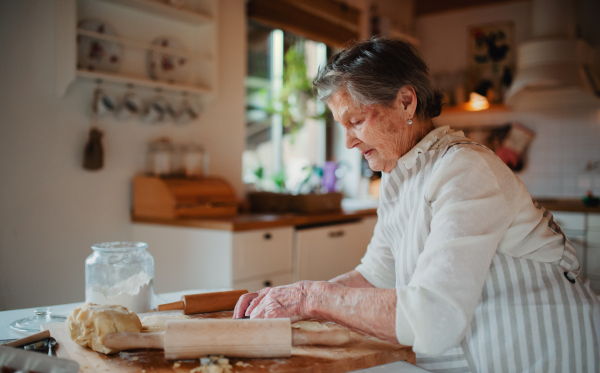 An elderly woman making cakes in a kitchen at home. Copy space.