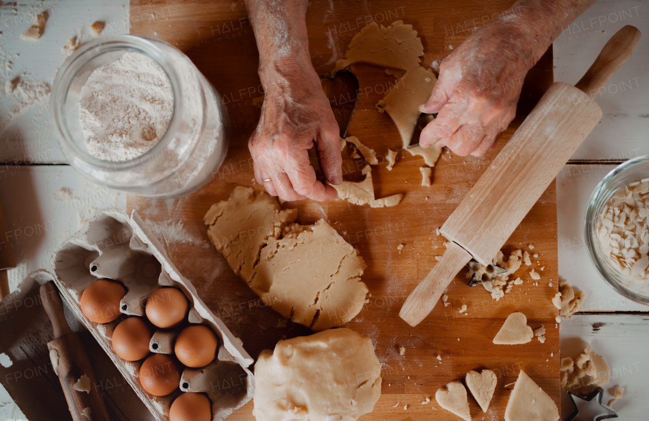 A midsection of old woman making cakes in a kitchen at home. Top view.