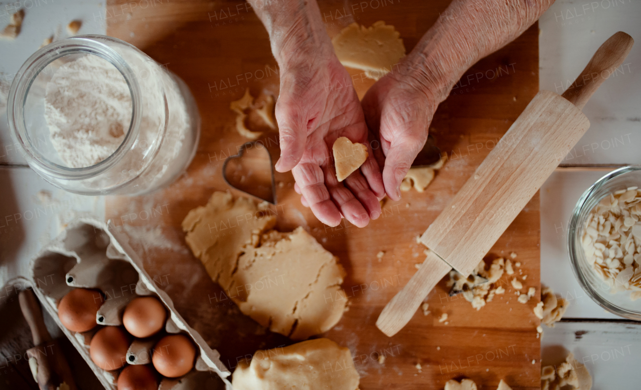 A midsection of old woman making cakes in a kitchen at home. Top view.