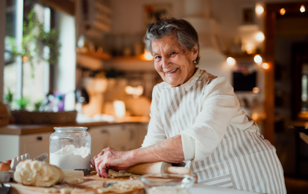 An elderly woman making cakes in a kitchen at home. Copy space.