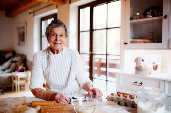 An elderly woman making cakes in a kitchen at home. Copy space.