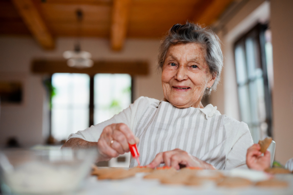 An elderly woman making and decorating cakes in a kitchen at home. Copy space.