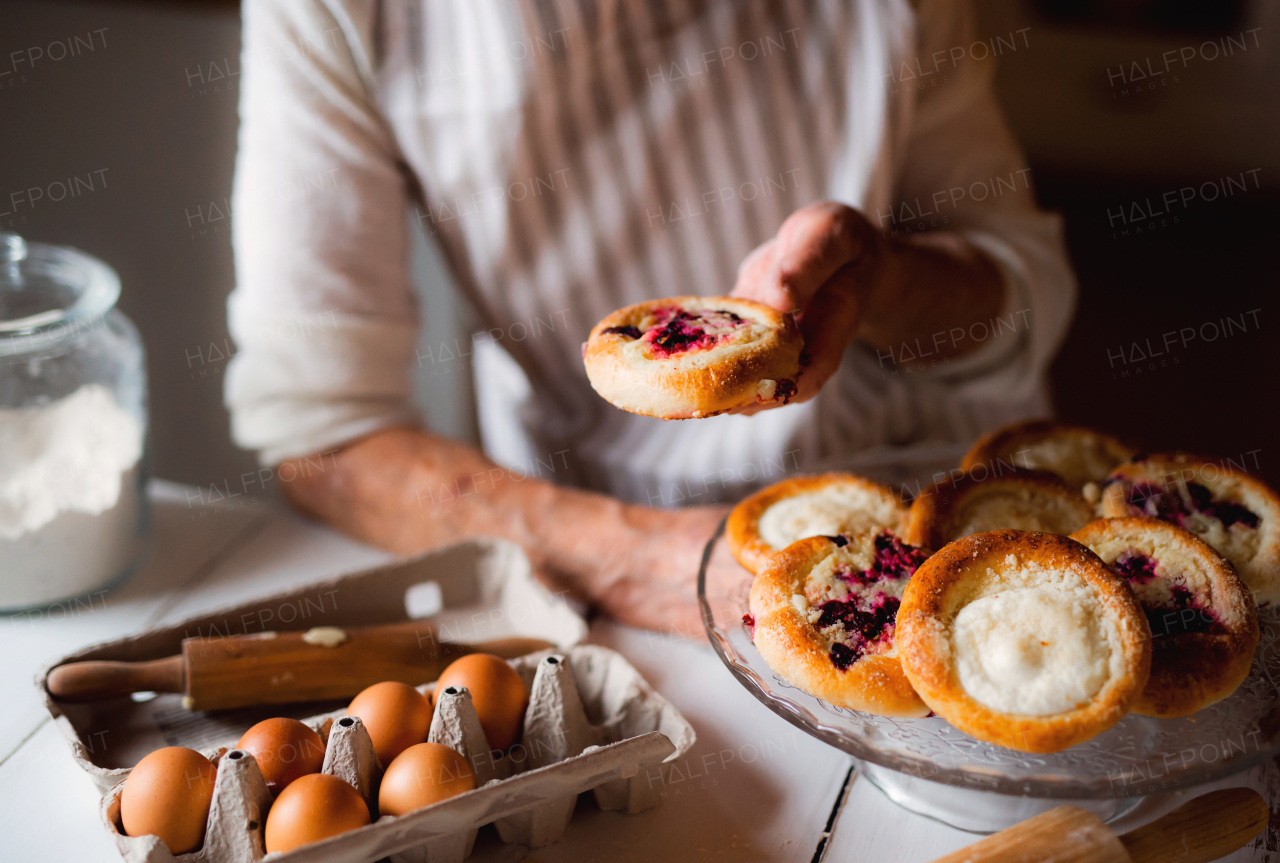 A midsection of unrecognizable senior grandmother making and holding cakes at home.