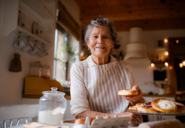 An elderly woman making cakes in a kitchen at home. Copy space.